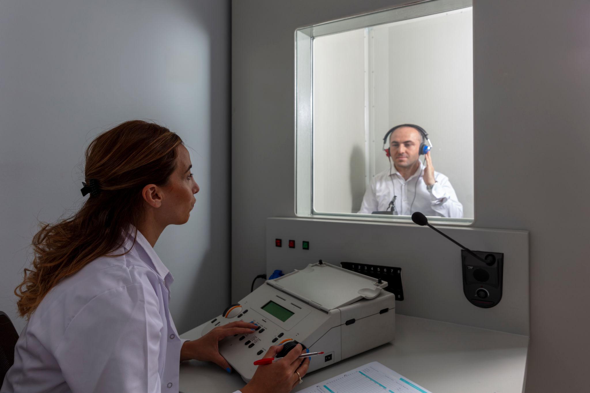 Audiologist conducting a hearing examination using an audiometer in a sound-treated room